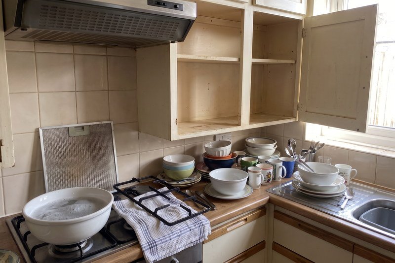 Kitchen mid deep clean with the cupboard doors open and the hob stripped down